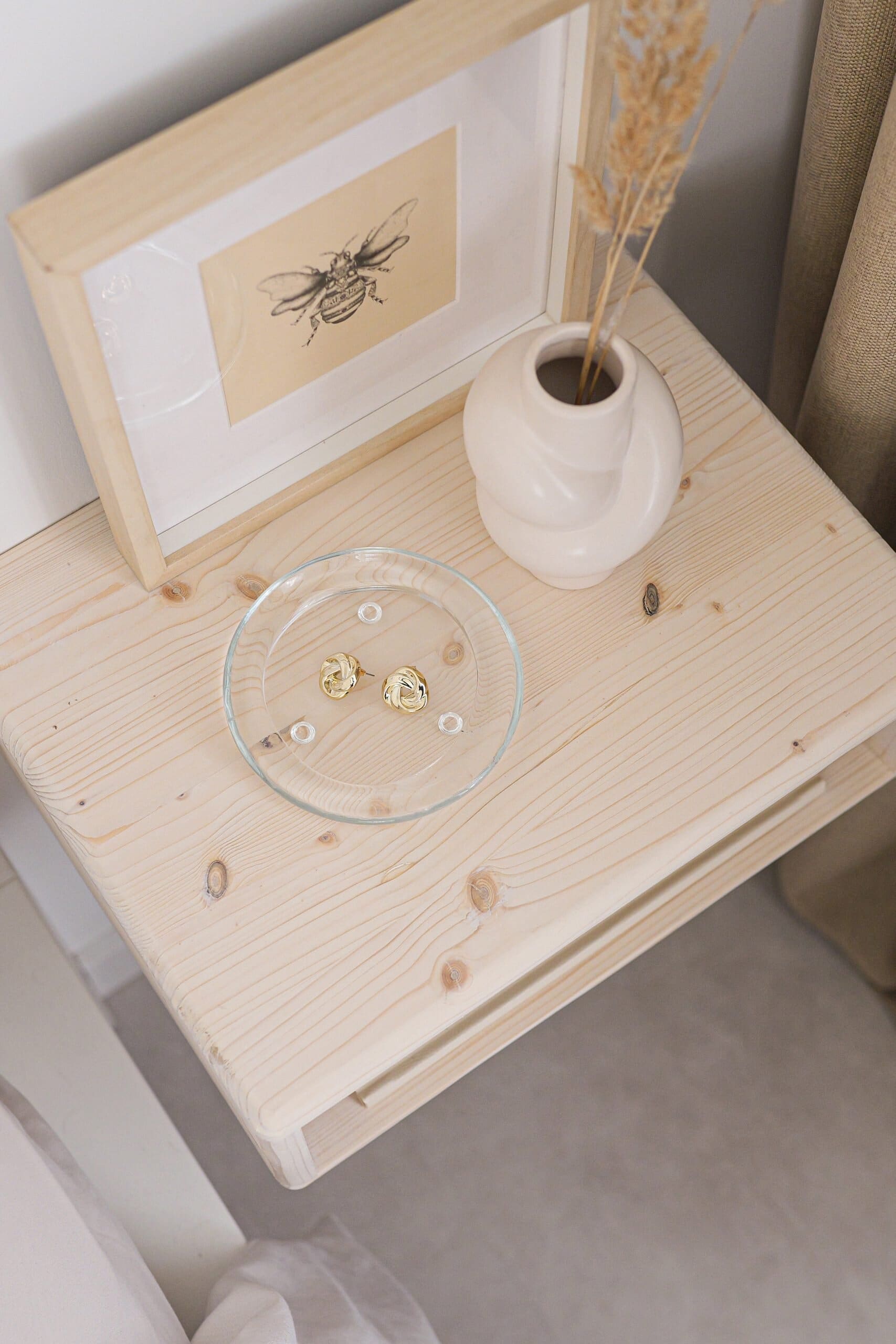 Heller Holznachtisch mit dekorativen Accessoires für modernes Schlafzimmer.